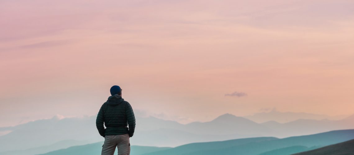 A hiker stands, viewing a horizon